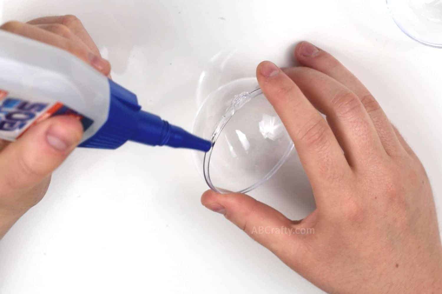 Applying loctite go2 glue to half of a clear fillable plastic ornament