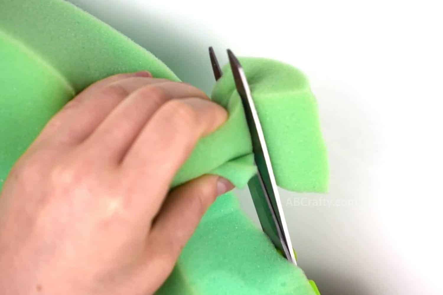 Using scissors to cut green foam