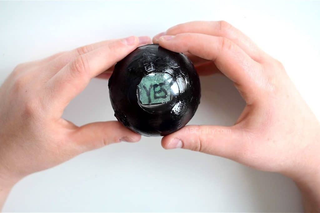 Magic 8 Ball held in hands showing an answer of 'yes'