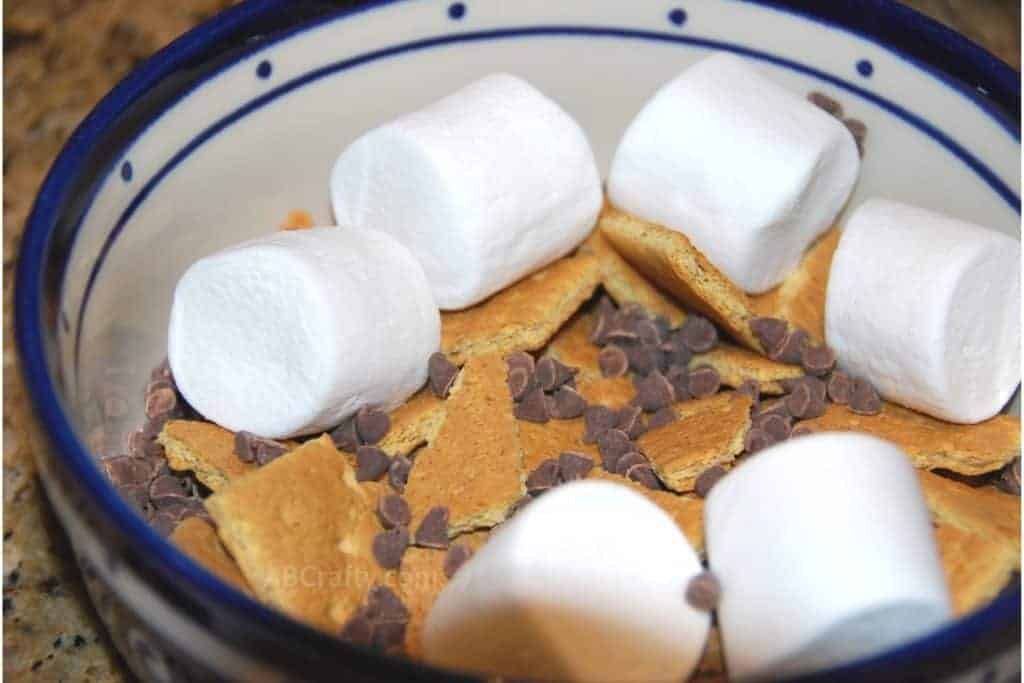 Marshmallows, chocolate chips, and broken up graham crackers in a ceramic bowl