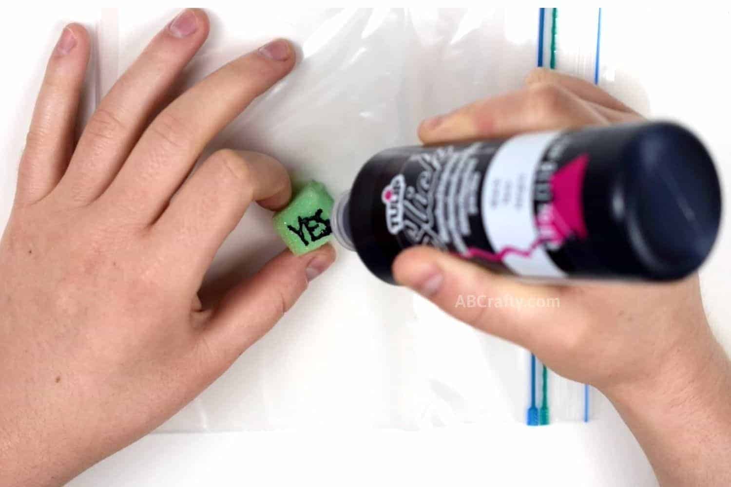 Writing "Yes" on a green foam cube with fabric paint that will be the answers for the magic 8 ball