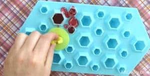 Placing the plastic from a ring pop onto the melted candy in the silicone mold