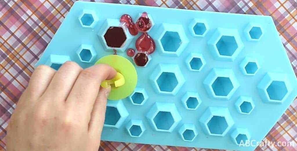 Placing the plastic from a ring pop onto the melted candy in the silicone mold