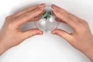 Pressing sides of a clear plastic ornament together with a the foam cube inside