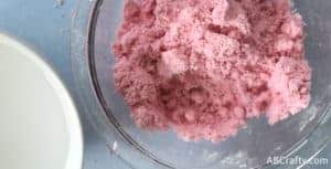 Red bath bomb mixture moistened to feel like wet sand