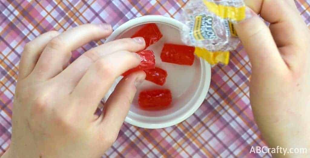 Unwrapping jolly rancher candies and placing them in a microwave safe dish