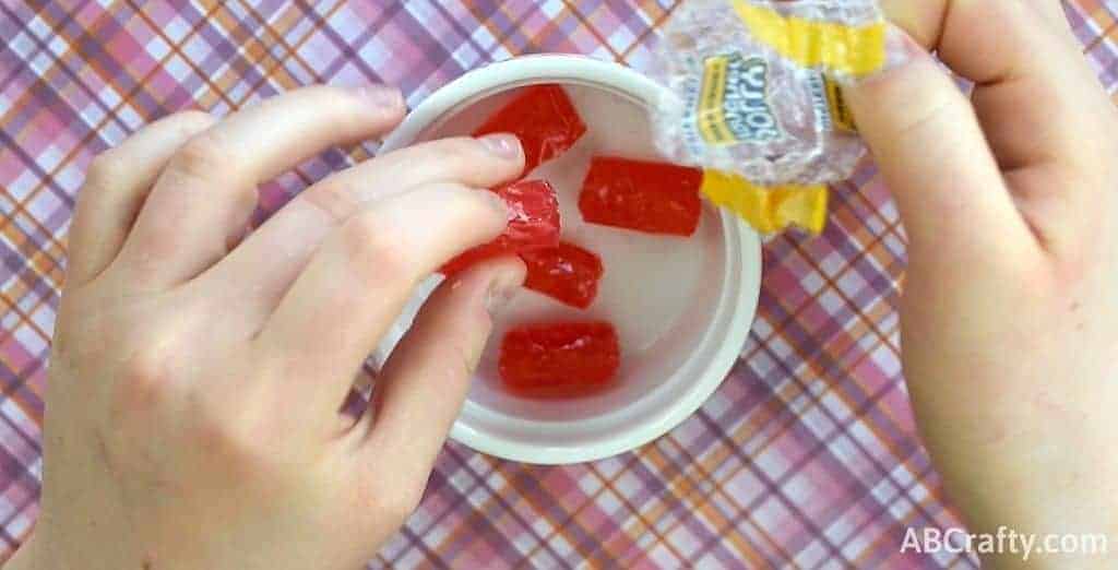 Unwrapping jolly rancher candies and placing them in a microwave safe dish