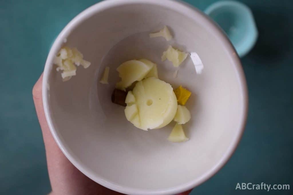 bowl with inside of an lip balm and some pieces of gold and yellow crayons