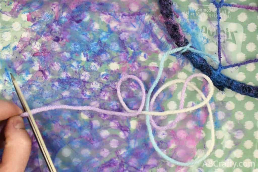 Cutting long length of yarn, attached to dream catcher covered in yarn