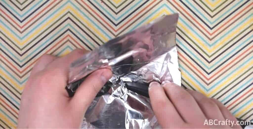 cutting a hole into a piece of aluminum foil with an exacto plade