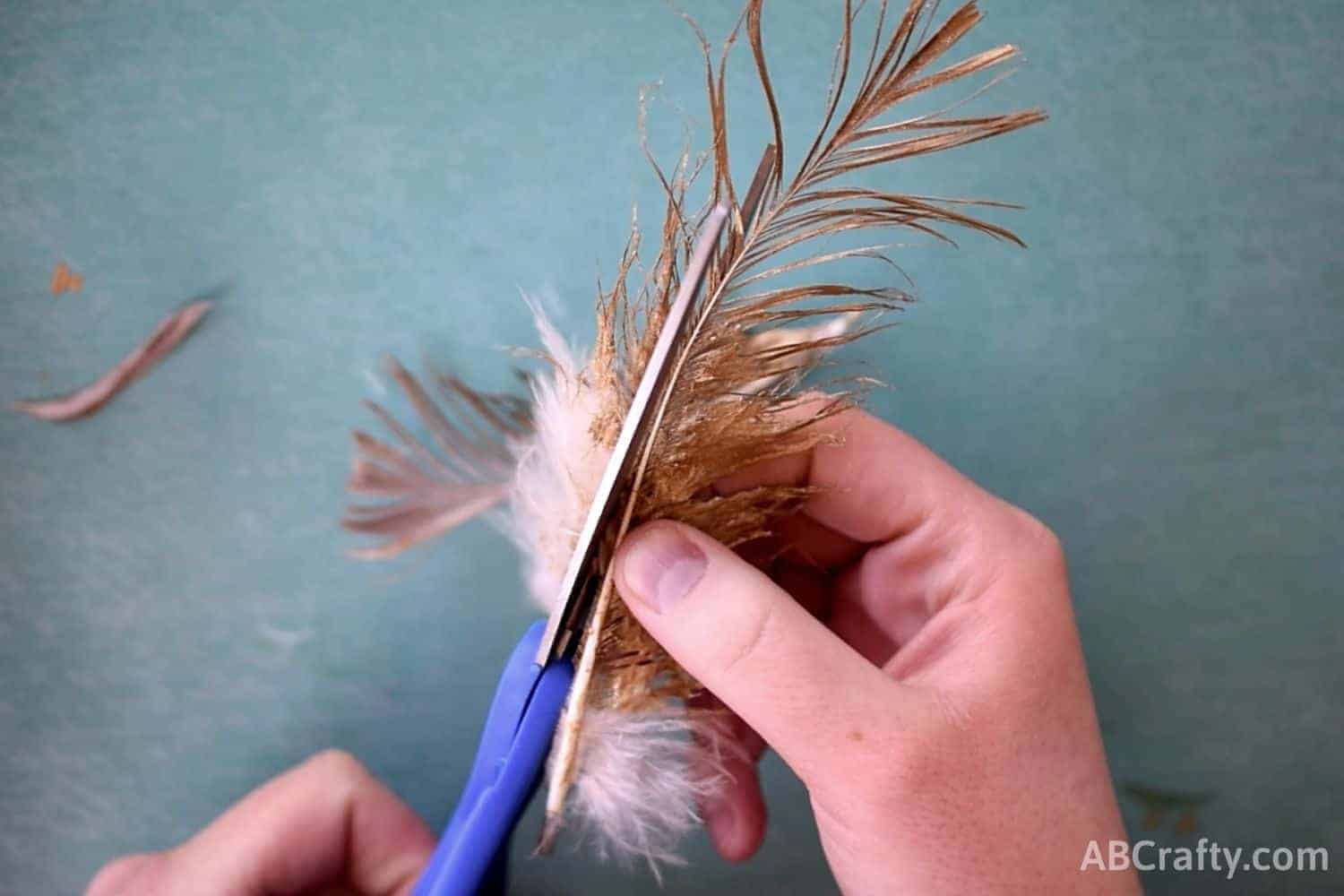 cutting the outside of off half of a feather that has been painted gold