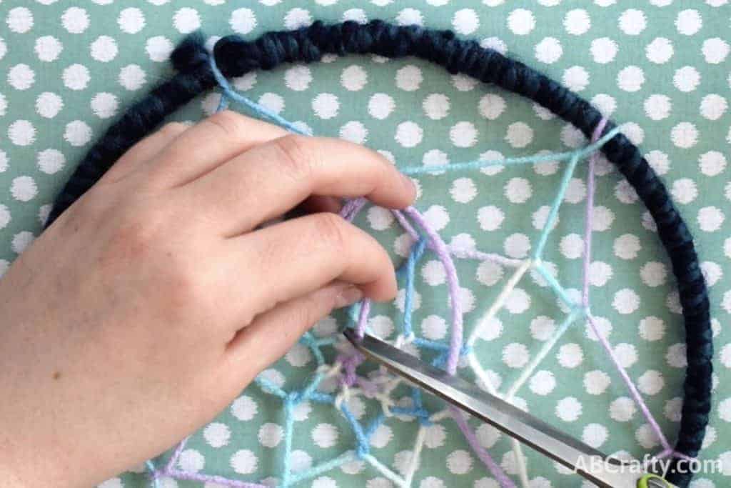 Cutting off the yarn at the center of the finished dream catcher web