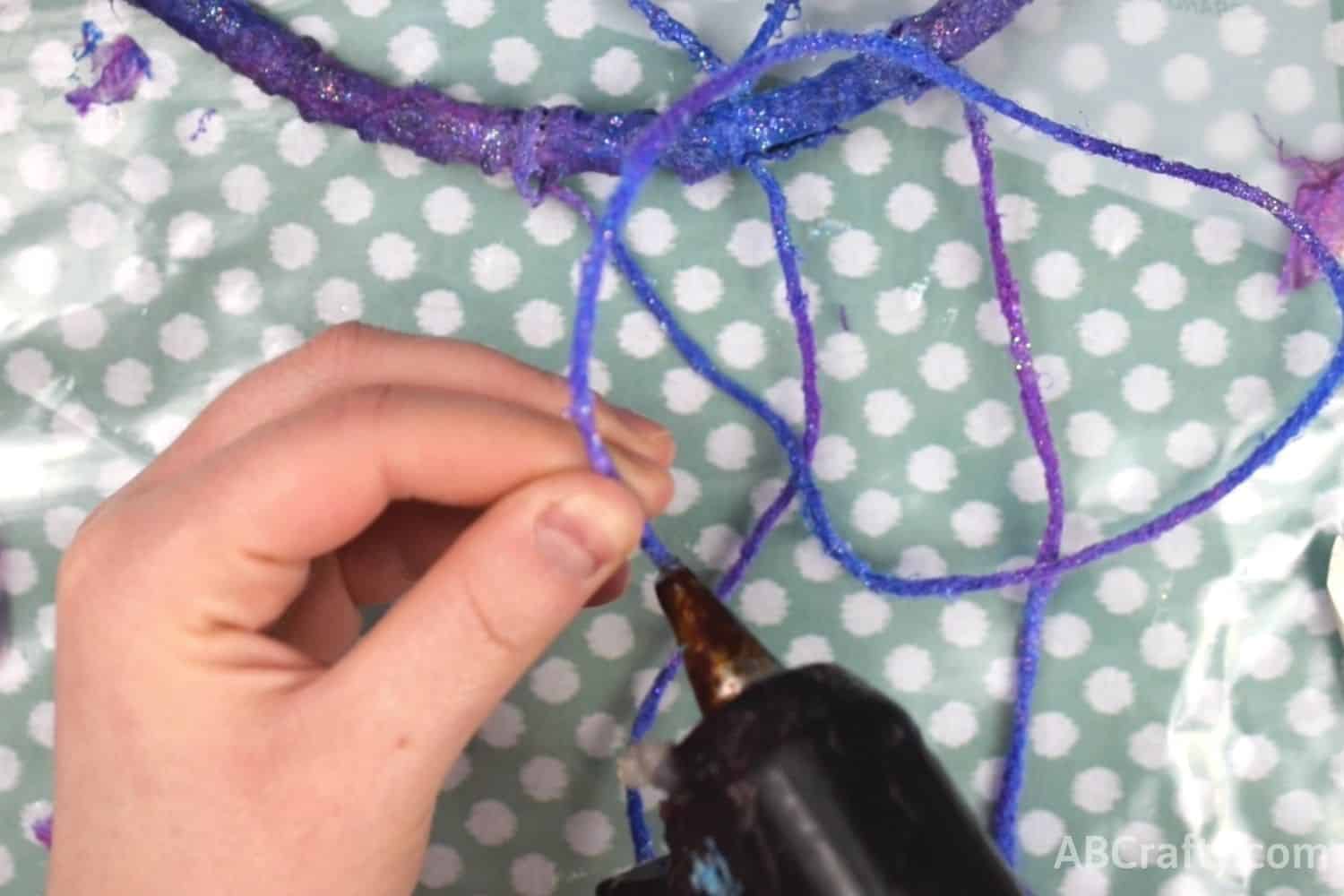 Using glue gun on the end of yarn painted in galaxy colors