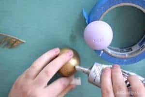 placing a dot of e6000 glue onto an eos lip balm that has been painted gold