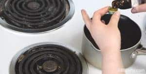 measuring flavoring extract over a pot of cooked candy on the stove