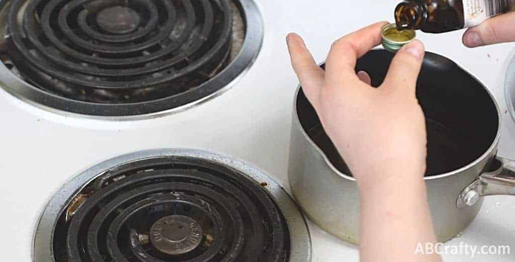 measuring flavoring extract over a pot of cooked candy on the stove