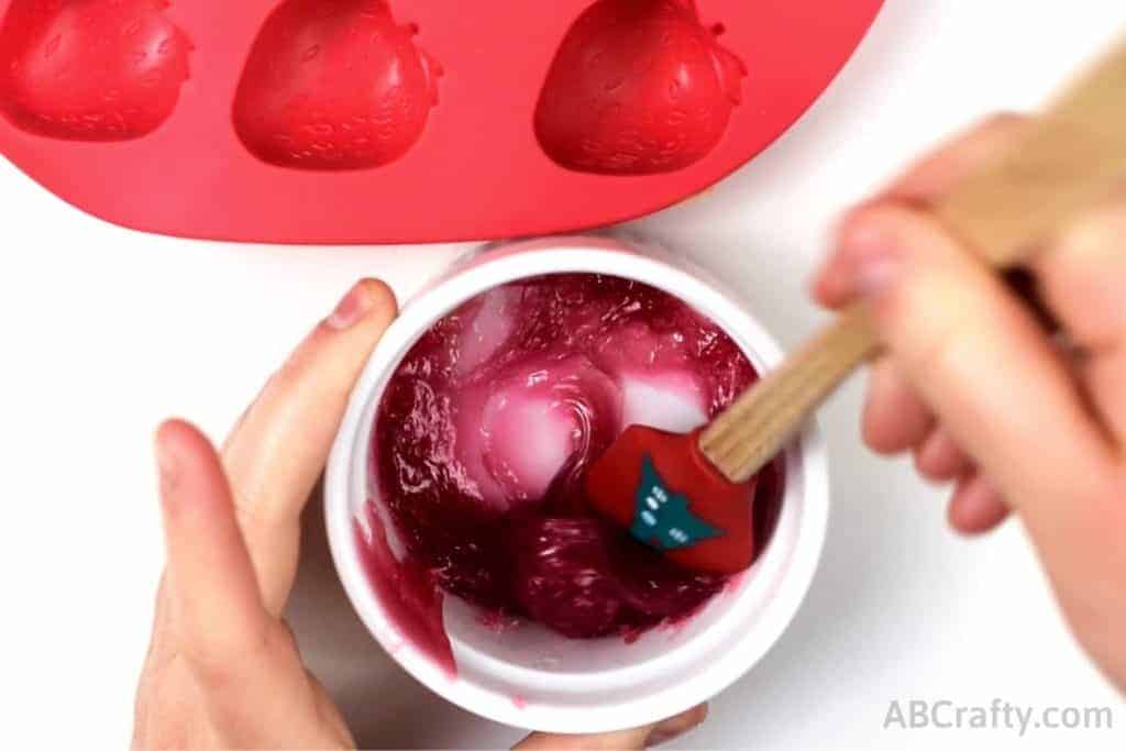 mixing melted pink candy gummies with a spatula