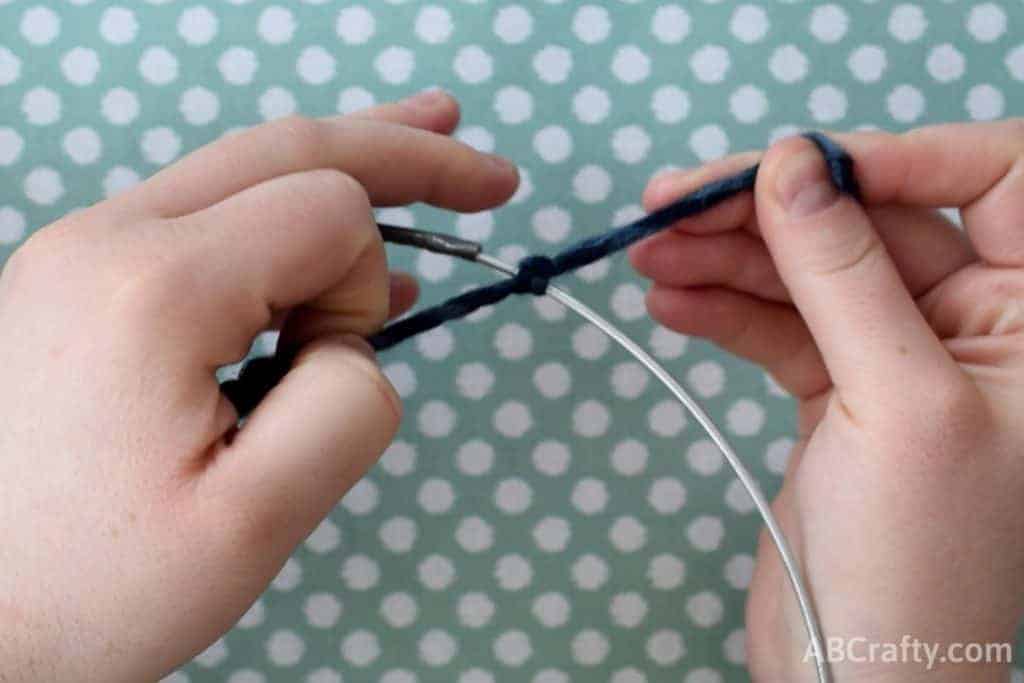 Tying yarn into a knot around a wire cirlce