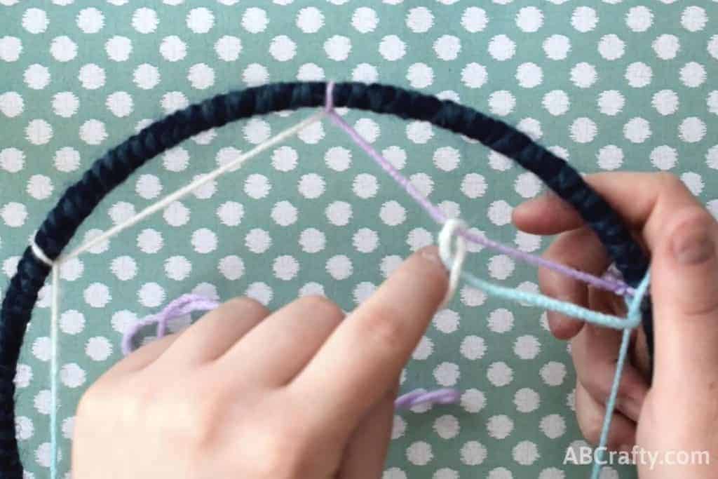 Tying yarn onto the center strand of yarn, attached to a hoop