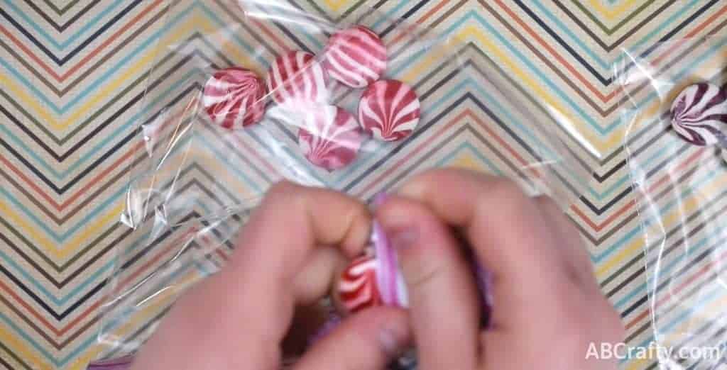 unwrapping red and white hard candy and putting it into a plastic bag