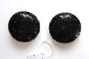 Plastic ornaments covered in black sequin fabric with a wire hanging out