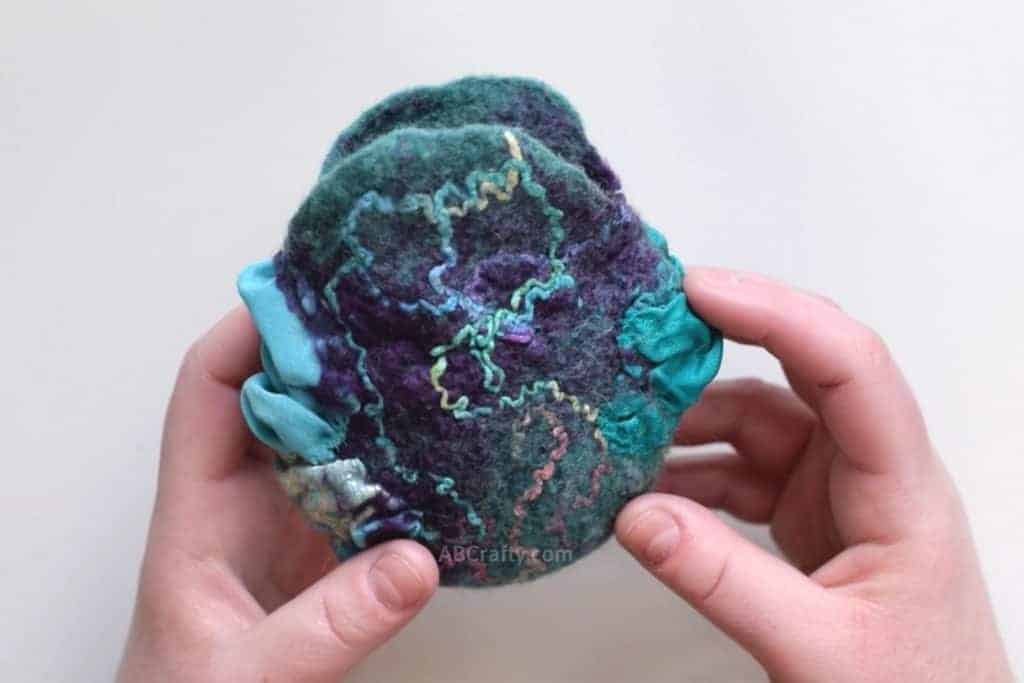 Teal and purple nuno felted coin pouch with teal and blue sari silk and rainbow yarn swirled on it
