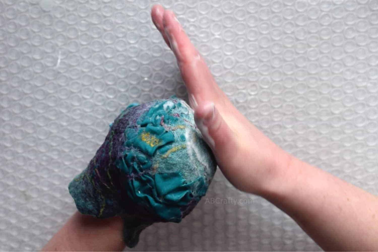 Felting change purse to make it round by putting one hand inside and rubbing from the outside