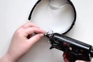 Folding and glueing down the end of a satin ribbon that is glued to a black sequin headband