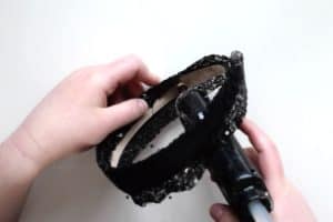 Using a glue gun to glue black sequin fabric onto the inside of a satin headband