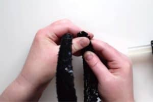 Pressing on the corner of a headband covered in black sequin fabric