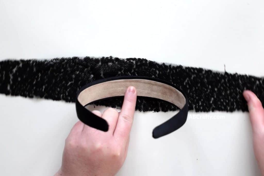 Glueing center of a black satin headband to a piece of black sequin fabric