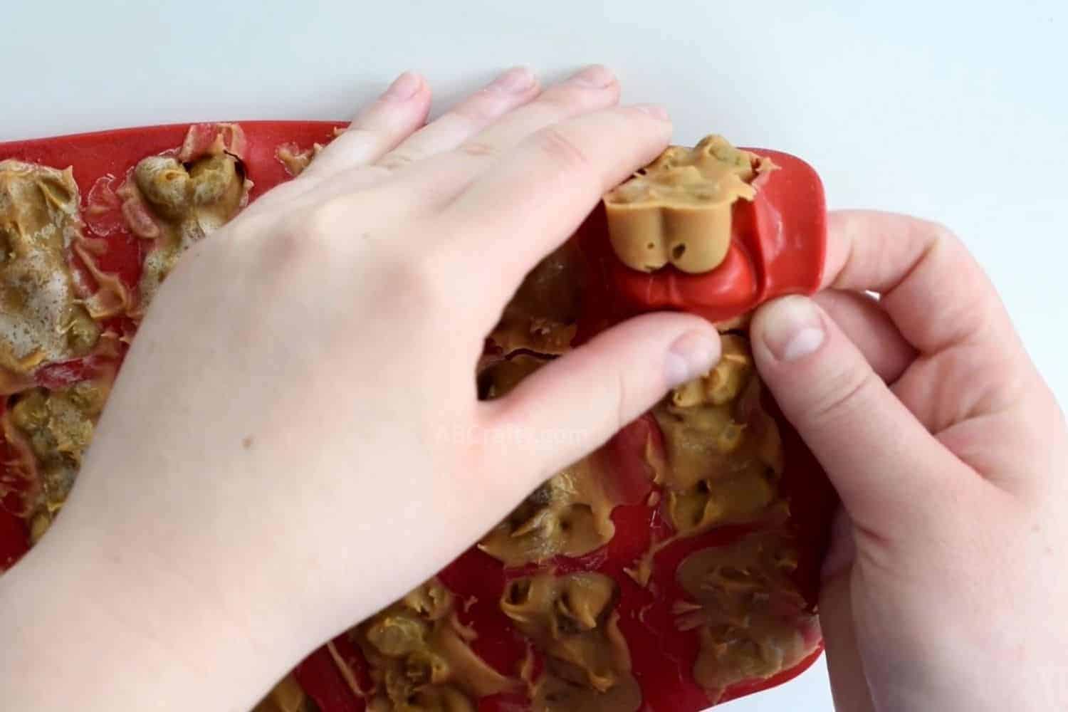 Removing peanut butter frozen dog treat from red silicone dog bone mold