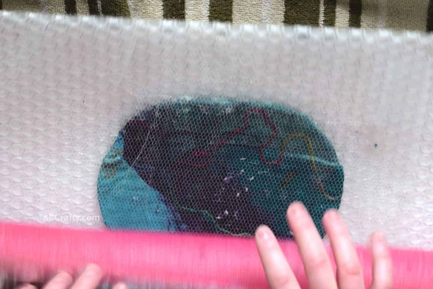Rolling the lightly felted and wet coin purse from the bottom with a pool noodle