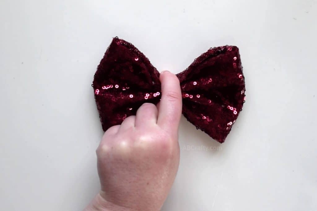 Holding center of handmade bow made of red sequin fabric