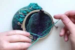 Tying embroidery thread into a knot after sewing on a kiss clasp