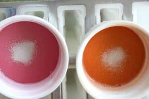 Orange and pink melted glycerin soap with white glitter in white ramekins