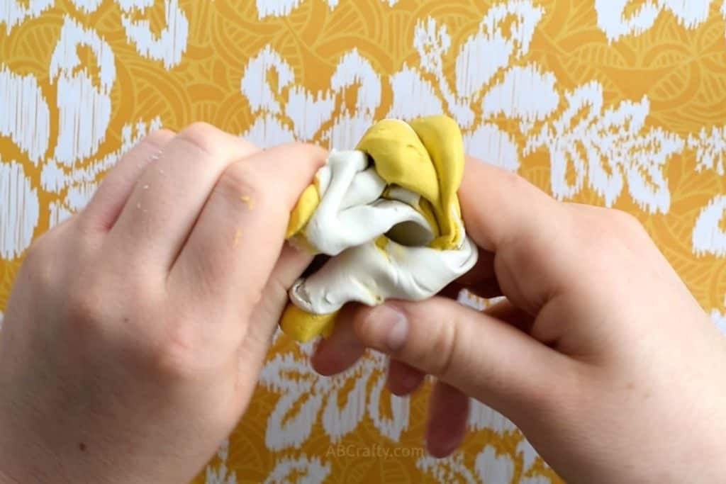 Mixing white and yellow mold putty together with hands