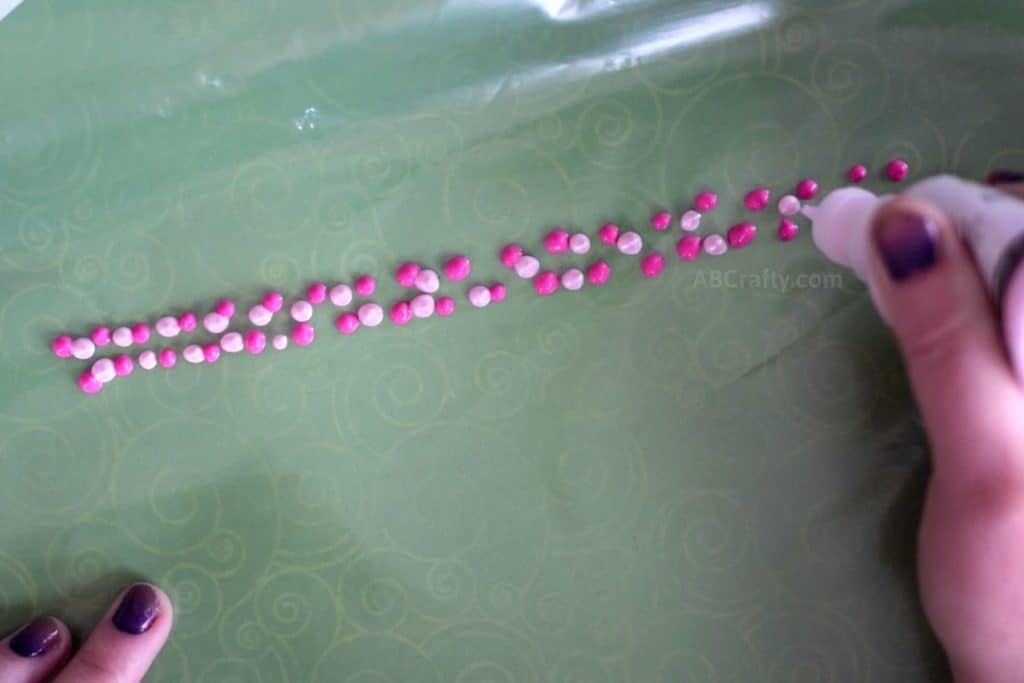 Adding dots light pink fabric paint between dots of bright pink fabric paint on a ziploc frezer bag
