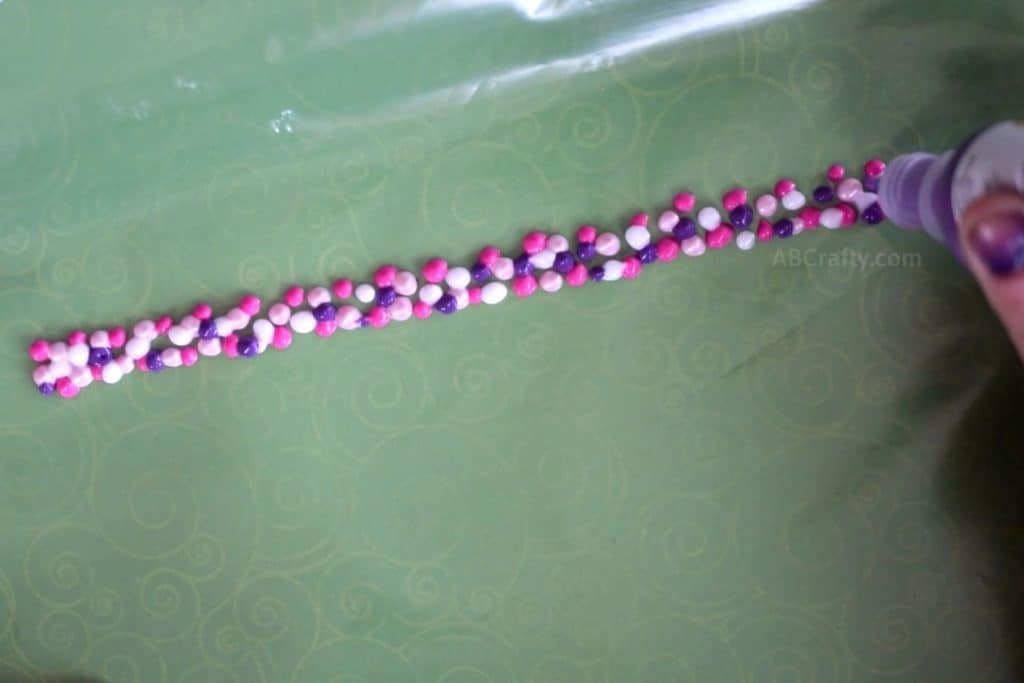 Dots of white, pinks, and purple fabric paint on a ziploc freezer bag