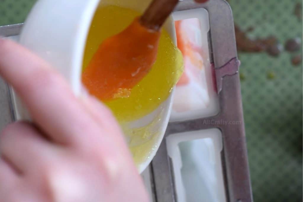 Pouring yellow glitter soap from a ramekin into mold