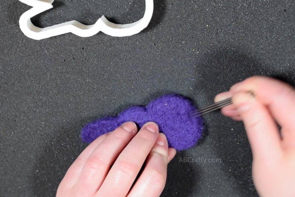 Using three felting needles to felt a purple marshmallow peep cat toy that's filled with catnip