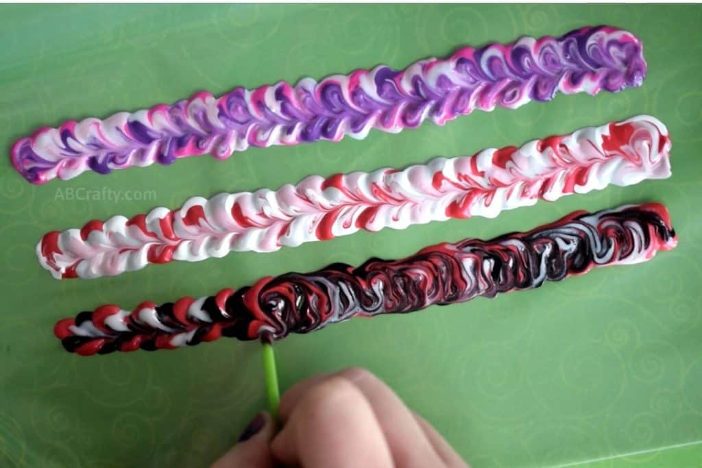 Swirling the last of three swirl bracelets made of fabric paint. One is pinks and purples, one is red, white and silver, and the last is red, black, and white