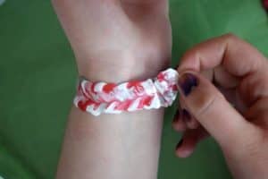 Peeling off white, pink, ready and glitter fabric paint swirl bracelet from around wrist