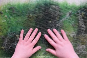 Rubbing hands over green wool and other fibers covered in mesh fabric