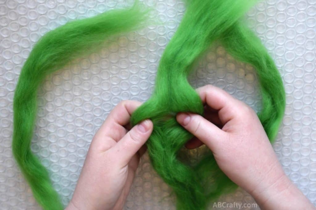 Separate green wool roving in half over bubble wrap