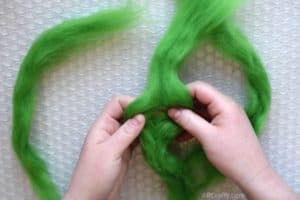 Separate green wool roving in half over bubble wrap