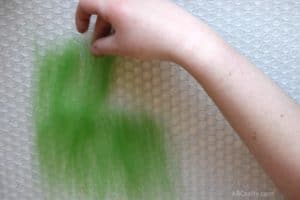 Placing small amounts of wool roving on top of bubble wrap, overlapping the edges of the wool in rows