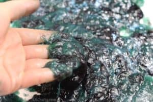 Lifting galaxy slime off the table. It's a mixture of purple, blue, and green slime with purple, blue, and white glitter on top