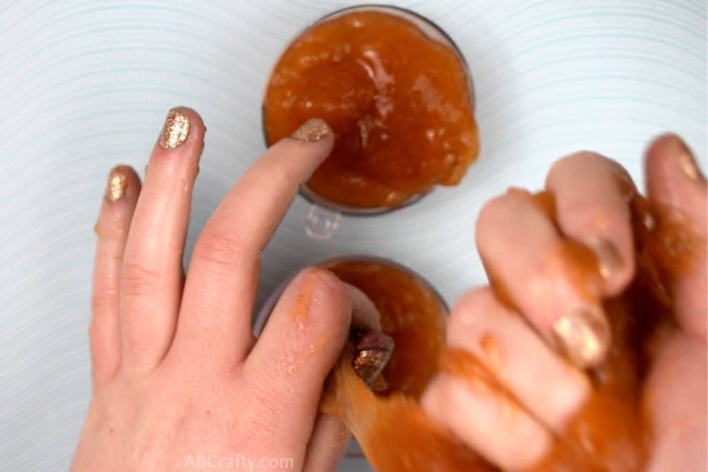 pouring orange slime into two halves of a plastic ornament