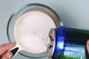 Pouring sprite into a 1 cup measuring cup over a glass bowl